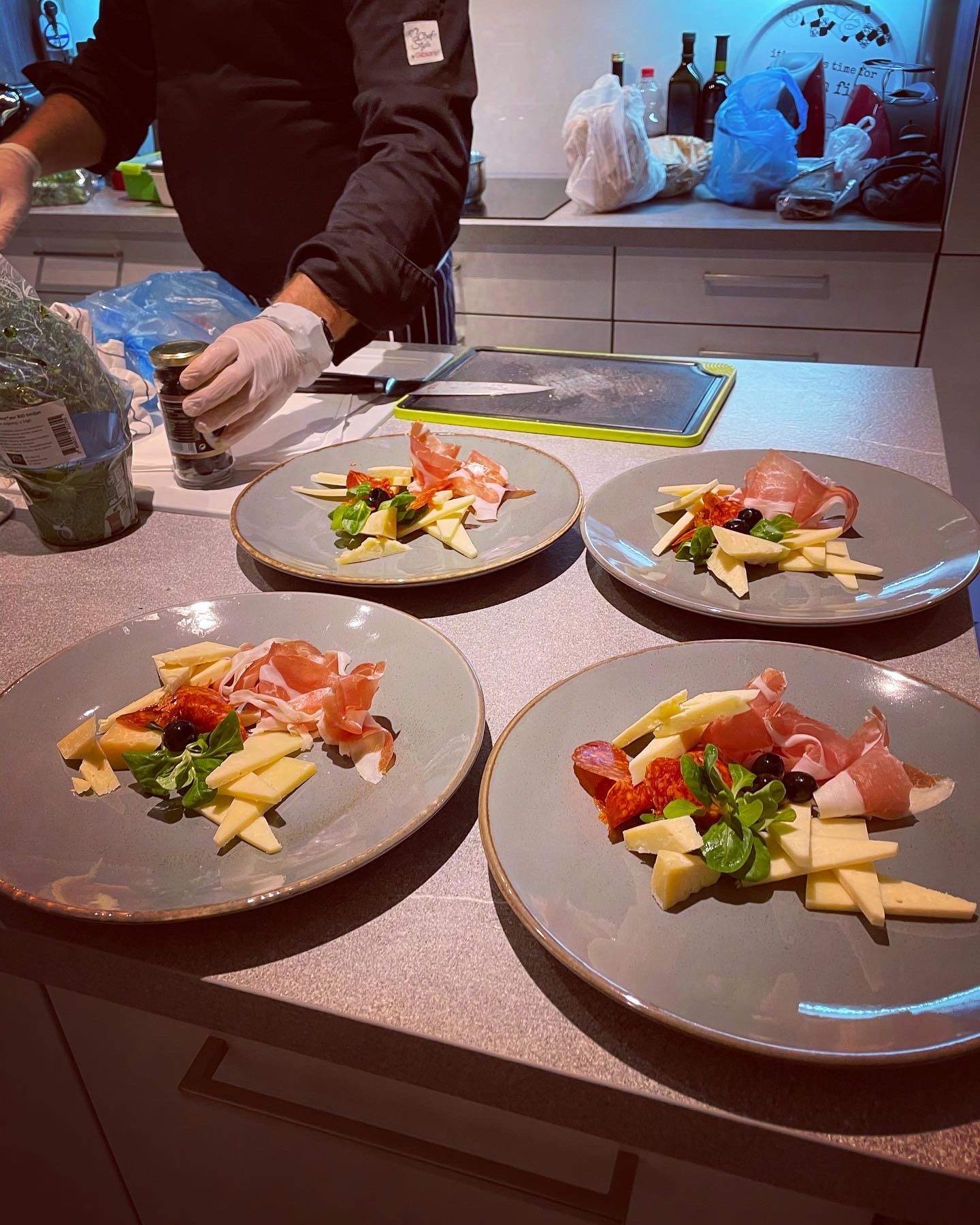 The private chef plating a starter of cheese, prosciutto and olives in the villa kitchen